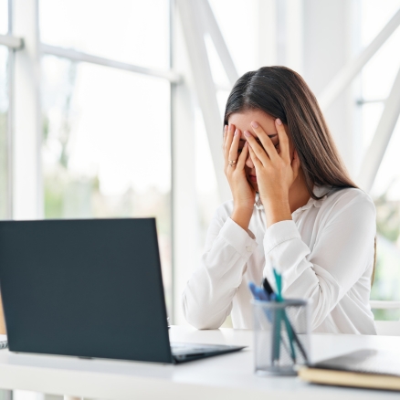 woman covering eyes by computer