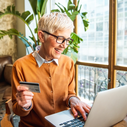 smiling woman with card and computer 