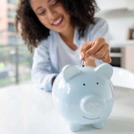 person putting money in piggy bank