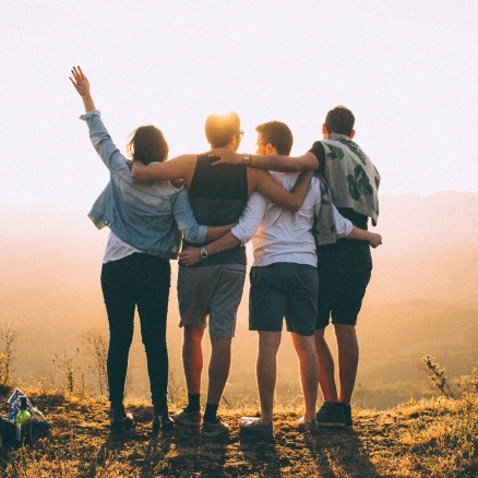 four people with arms around each other 