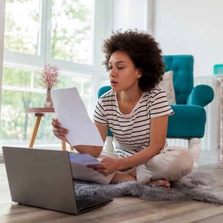 woman looking at paper and computer
