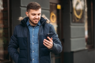 man in puffy jacket smiling at phone