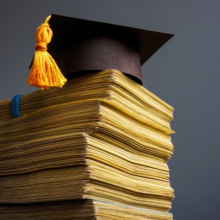 graduation cap on a pile of money