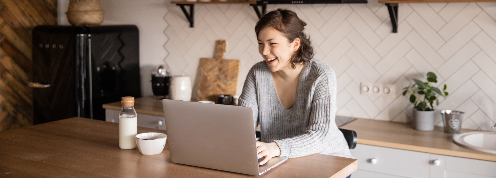 Brown haired woman smiling in kitchen 
