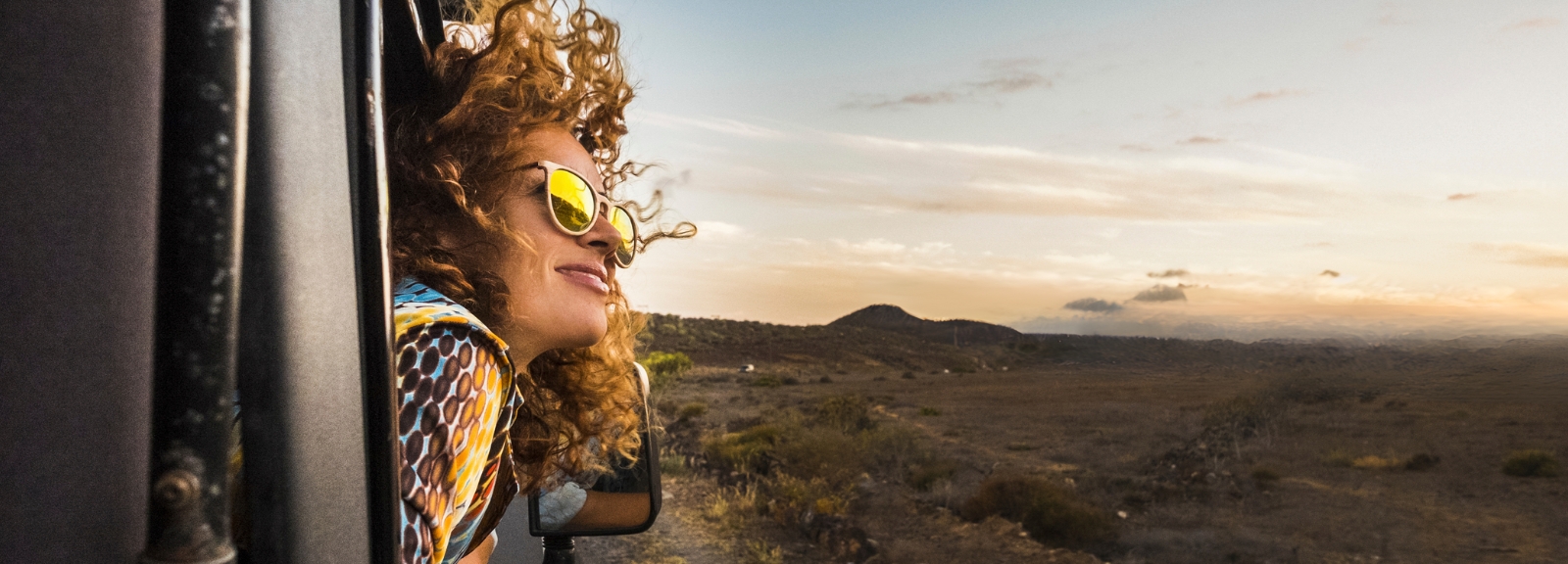 woman in sunglasses with face out of car window