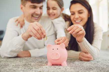 family of 3 around a piggy bank