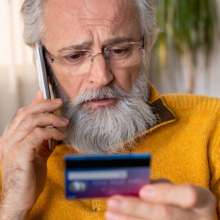 Man looking at credit card while on phone