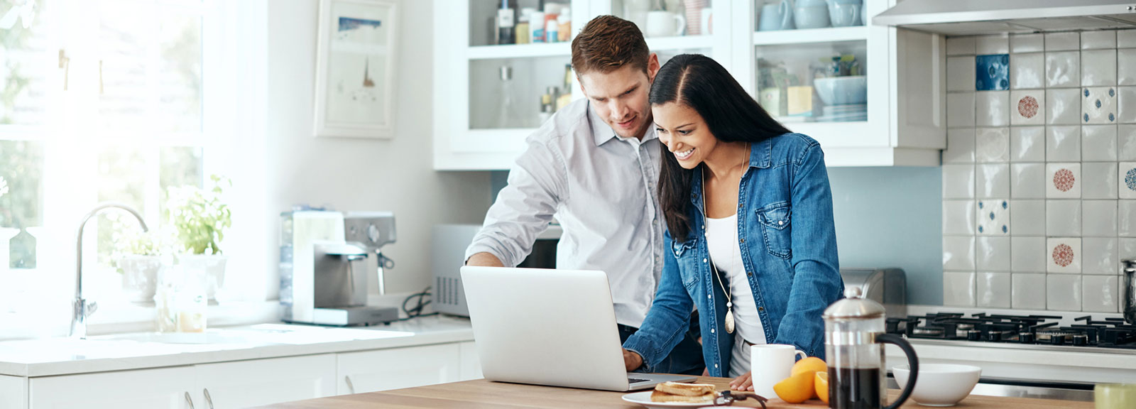 Young couple working on laptop in kitchen