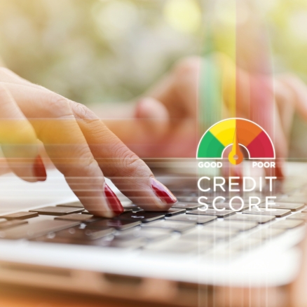 woman with red nails typing on the computer with a credit score image next to her hands
