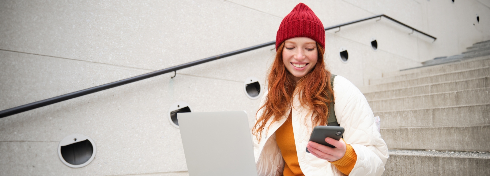 young woman looking at phone and computer
