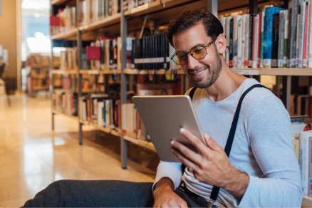 man reading tablet in library