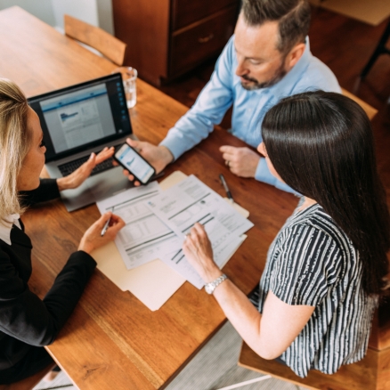 three people looking at paperwork and computer 