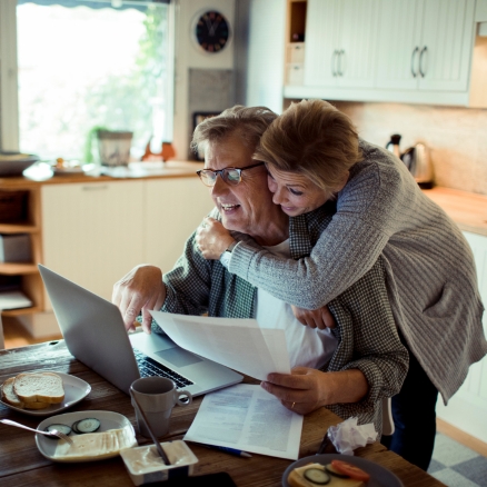 couple smiling at computer with papers